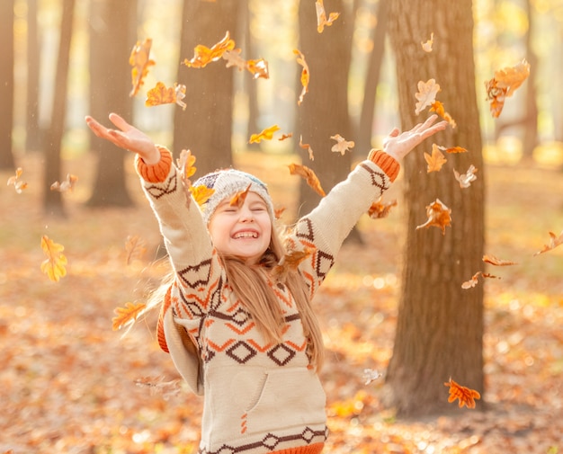 Photo little girl throwing up leaves