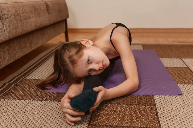 Little girl trains at home on the floor.