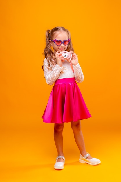 little girl traveling contains a camera on a yellow background