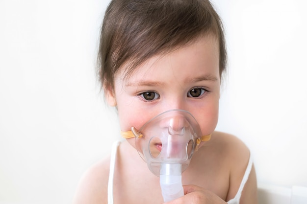 The little girl treats cough and runny nose. The girl sits with inhalation