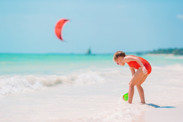 Little girl at tropical white beach making sand castle