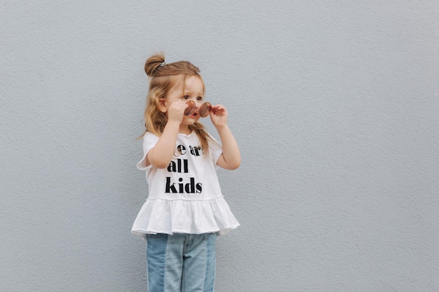 Little girl try on sunglasses and posing to photographer