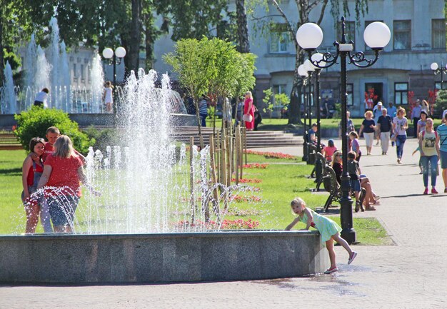 Photo little girl trying to touch water in city fountains lifestyle concept