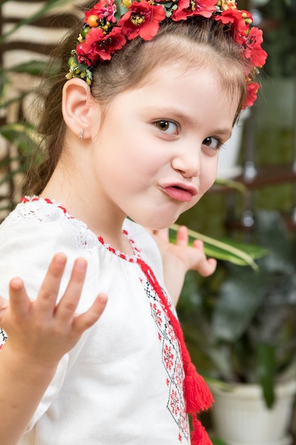 Little girl in the Ukrainian embroidery emotionally throws up his hands