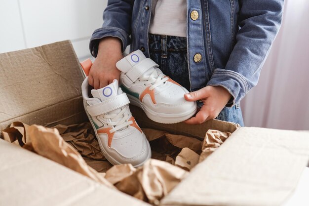 A little girl unpacks the parcel sneakers in her hands