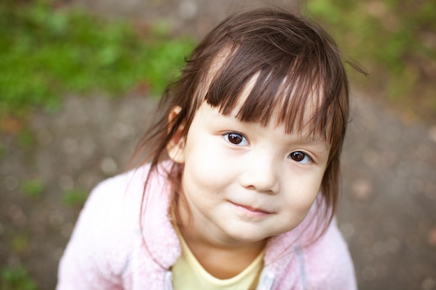 La bambina in un contesto urbano sorride alla macchina fotografica.