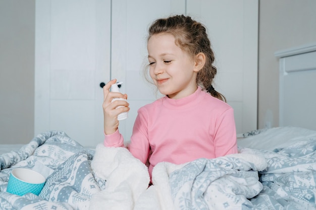 Little girl use inhaler nebulizer lying in bed in bedroom Child asthma inhaler nebulizer steam flu or cold concept Copyspace