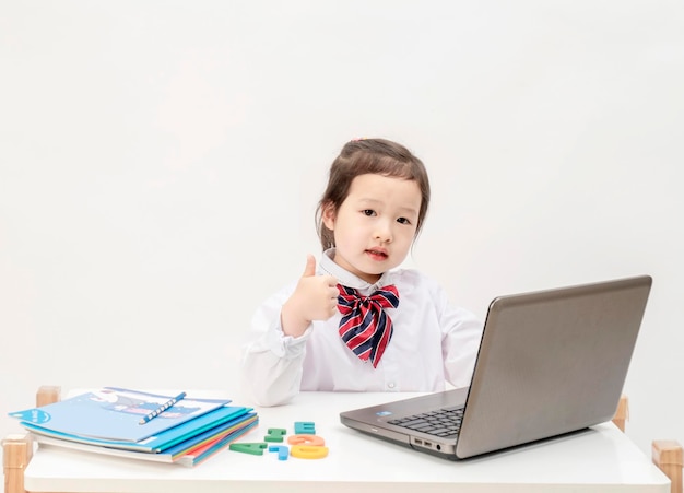 The little girl uses her laptop to surf the Internet for class