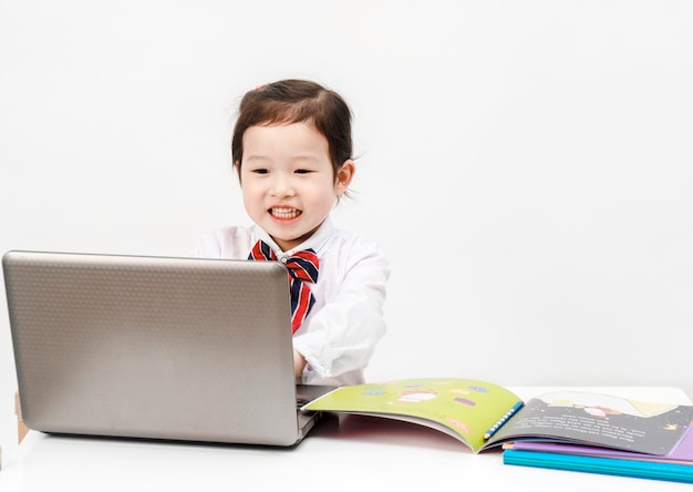 小さな女の子はクラスのためにインターネットをサーフィンするために彼女のラップトップを使用しています