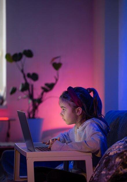 A little girl uses a laptop late at night