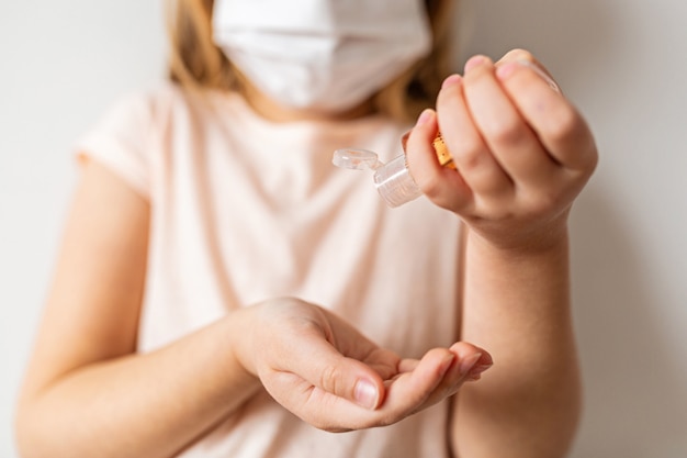 Bambina che usando il gel dell'alcool del disinfettante della mano per le mani pulite