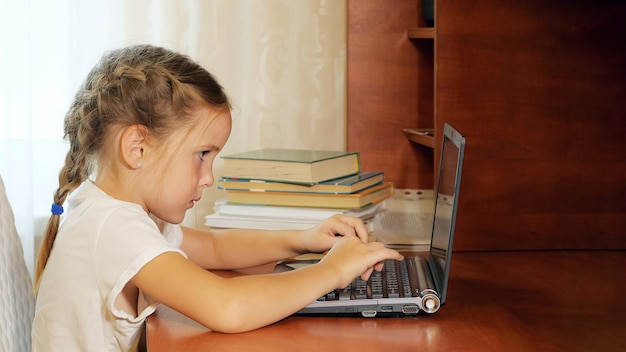 Little girl using laptop at desk