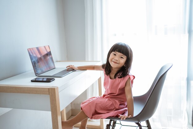 Bambina che per mezzo del computer portatile a casa