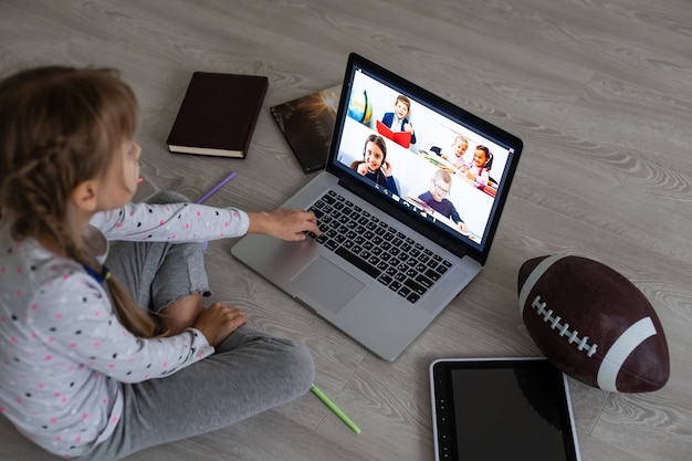 Photo little girl using video chat on laptop at home. space for text