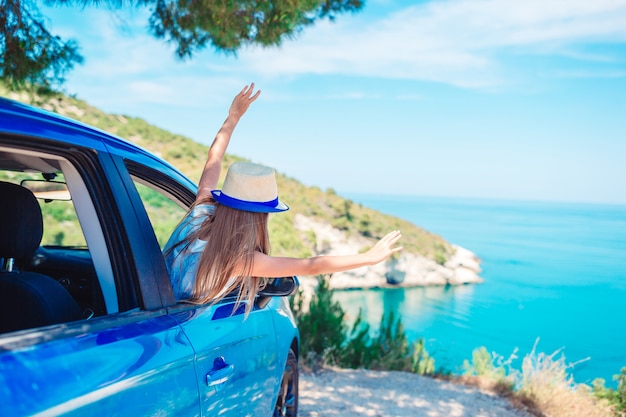 Little girl on vacation travel by car on beautiful landscape