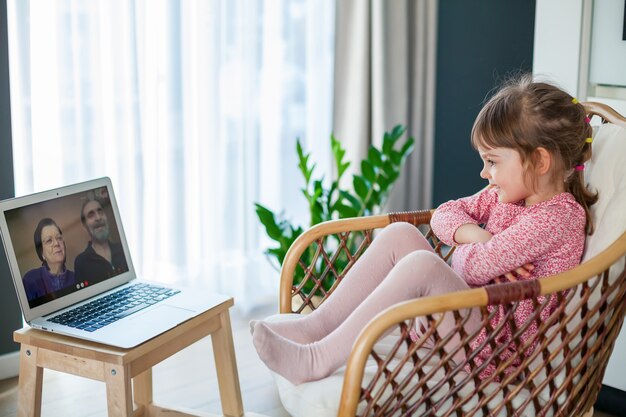 Little girl video-chatting with her grandparents using laptop