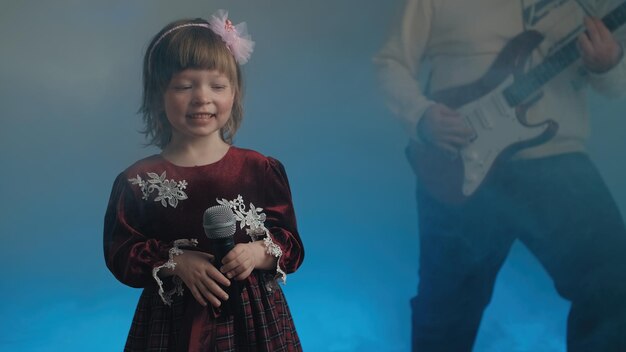 Photo little girl in vintage dress sings on stage her father plays an electric guitar