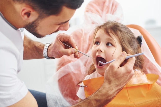 Photo little girl visiting male dentist in clinic conception of stomatology