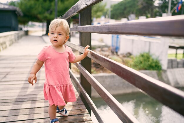 Little girl walking on the bridge over the river