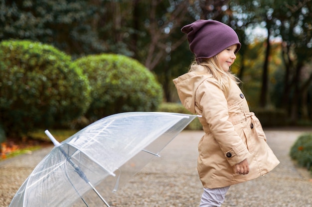 Little girl walking in a park under an umbrella during a rain