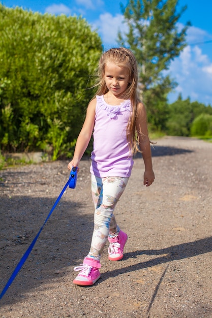 Photo little girl walking with her dog on a leash