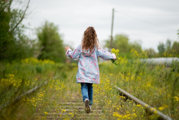 A little girl walks along the grassy railroad tracks Ecology