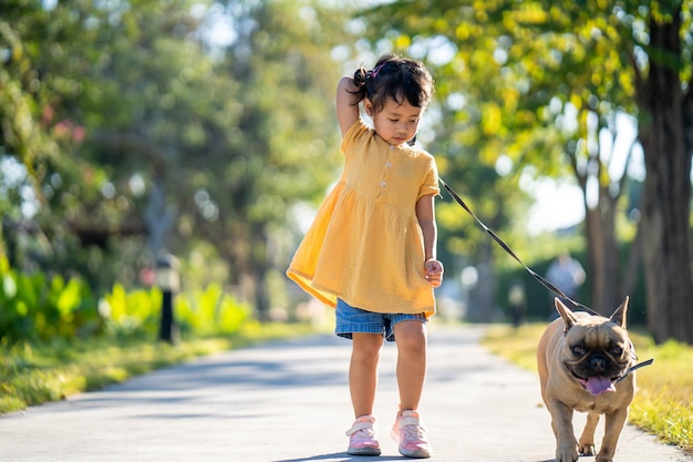 小さな女の子がリードにつないで犬の散歩をしている