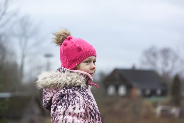 Little girl walks outdoors in autumn day in countryside.