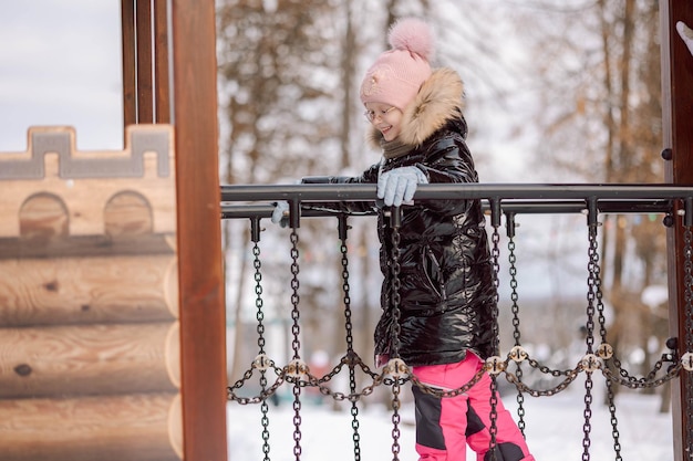 小さな女の子が冬の雪の日公園で屋外を歩いています