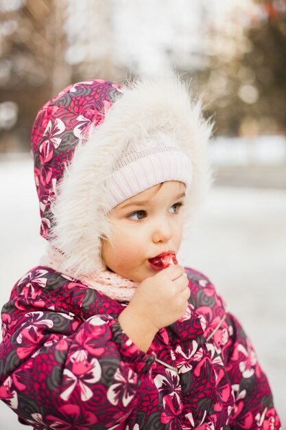 A little girl walks in the winter with a Lollipop