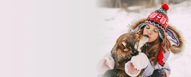 A little girl walks with her dog in the winter forest