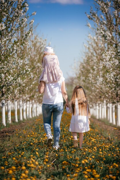 A little girl walks with her mother in a flowering garden Beautiful spring