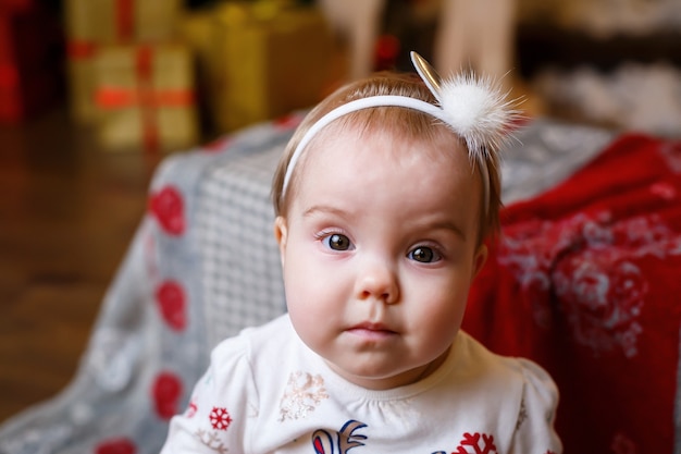 Una bambina con un maglione caldo sta con un albero di natale con giocattoli e regali. buona infanzia atmosfera festosa di capodanno