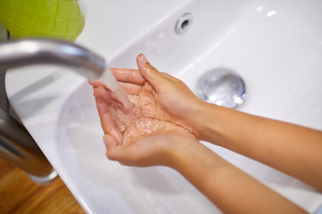 Little girl washing hands with soap in the bathroom