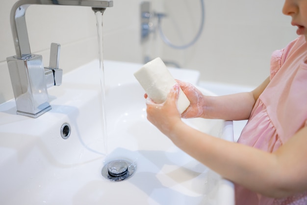 Little girl washing her hands with soap