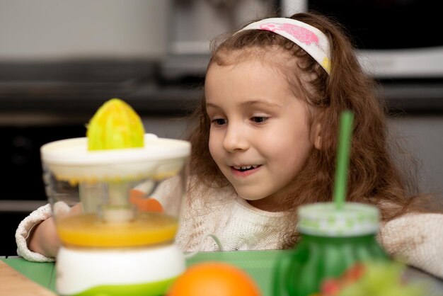 オレンジジュースが準備されているのを見ている少女新鮮な果物健康的な食事