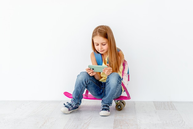 Little girl watching phone, sitting on skate