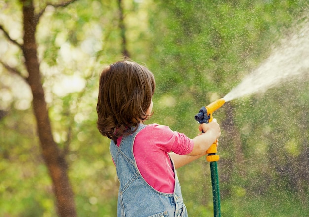 Little girl watering garden