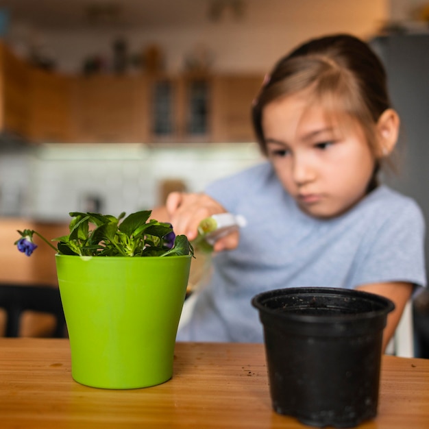 写真 鍋の植物に水をまく少女