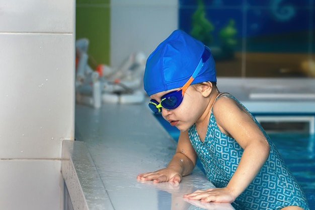 屋内プールの水泳教室で防水ゴーグルと水着を着た少女