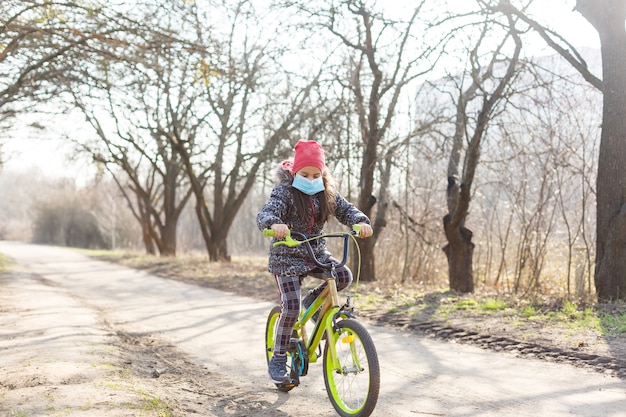 Bambina che indossa maschera antinquinamento sulla sua bici al parco.