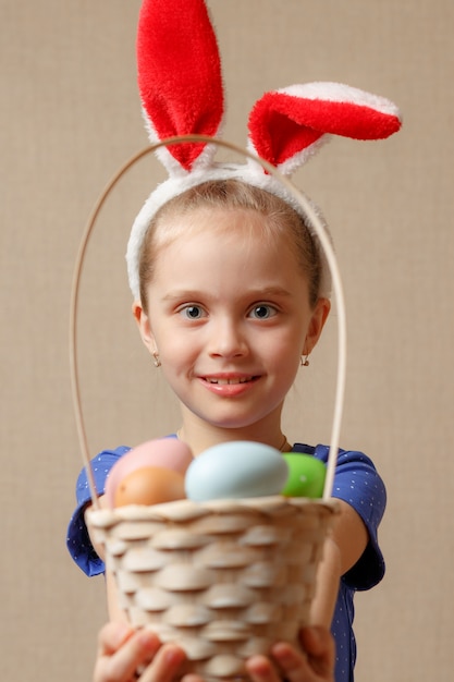 Photo little girl wearing bunny ears holding a basket with easter eggs