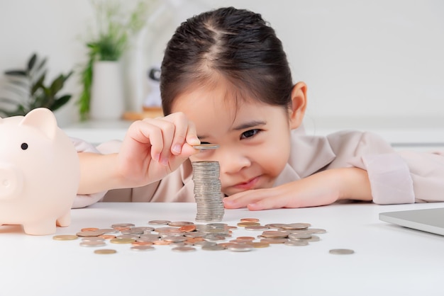 little girl wearing a cream suit analyzing coins concept of finance and investment in white room