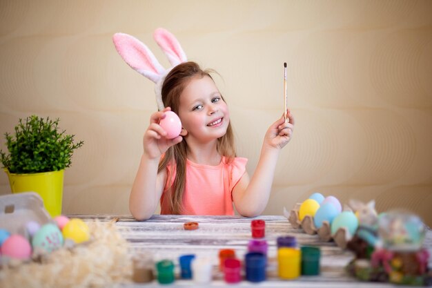 Little girl wearing easter bunny ears painting easter eggs at home prepares to easter happy easter