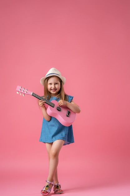 Little girl wearing a hat and a ukulele guitar