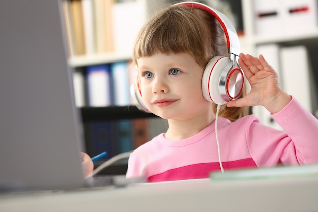 Little girl wearing headphones use mobile computer