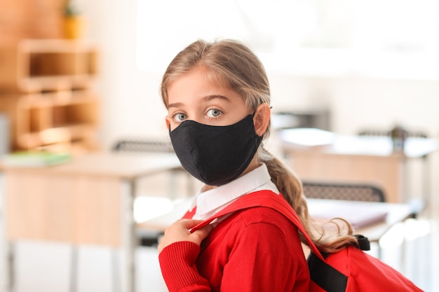 Little girl wearing medical mask at school