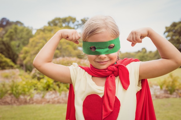 Little girl wearing superhero costume contracting biceps