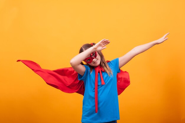 Little girl wearing superman costume ready to fly off in studio over yellow background person