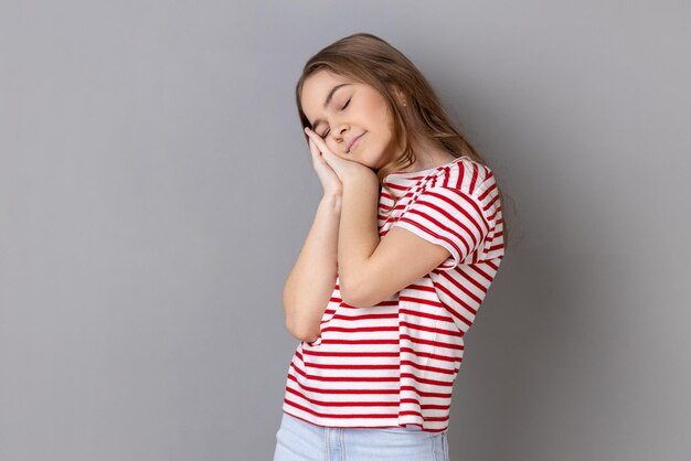 Little girl wearing Tshirt yawning and covering mouth with hand feeling exhausted lack of sleep